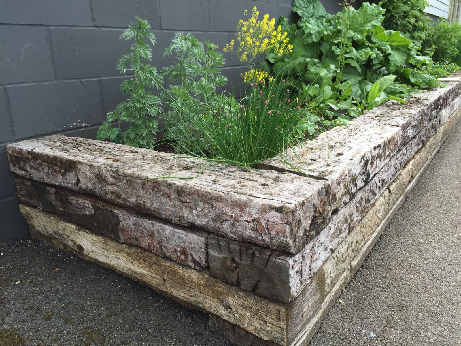 Railway sleepers stacked on top of each other to build a raised planter. Railwaysleepers.com