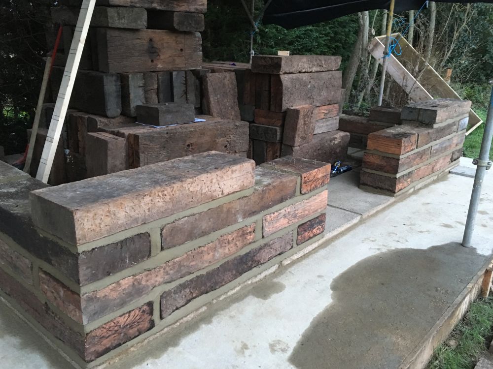 Fixing short lengths of used railway sleepers together with mortar to create a 'wooden brick' built building. Railwaysleepers.com