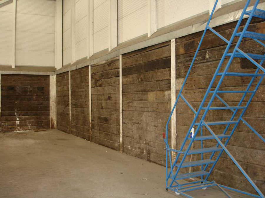 Internal factory wall made from used railway sleepers slotted into steel RSJs. Railwaysleepers.com